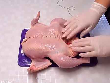 Будующая фаршированная курица зашивается в районе груди